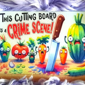 May include: A rectangular cutting board with the text "THIS CUTTING BOARD IS A CRIME SCENE!" features cartoon vegetables with terrified expressions. A large knife is plunged into the board, with a pool of red liquid. The board is on a fluffy, purple surface.