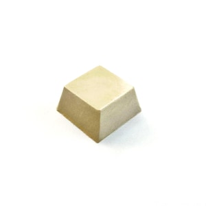 May include: A light beige, square-shaped object with a trapezoidal top, set against a plain white background. The object's edges are slightly rounded. The overall design is minimalist and clean.