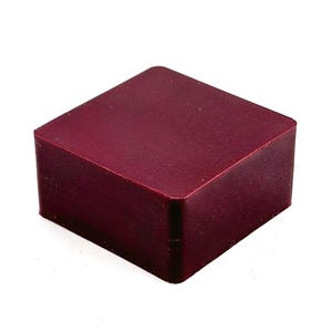 May include: A solid, square block in a deep burgundy color. The block has rounded corners and a smooth, matte finish. The object is isolated against a white background.