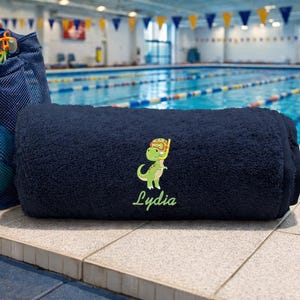 Personalised Boys Swimming Towel Embroidered with Dinosaur and Child's Name By the side of a swimming Pool