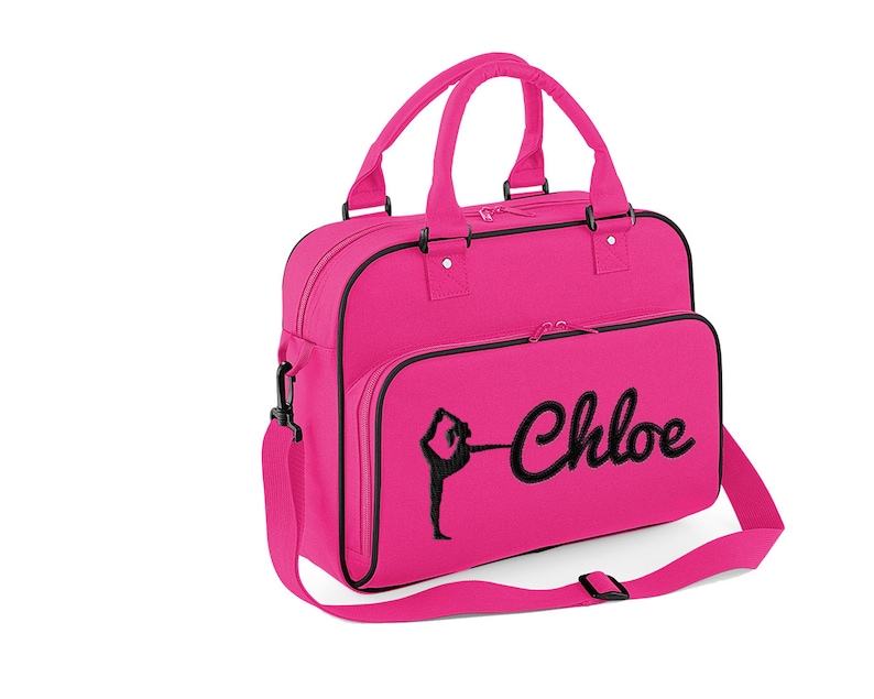 May include: A pink canvas gym bag with a black zipper and a black embroidered silhouette of a gymnast and the name "Chloe".
