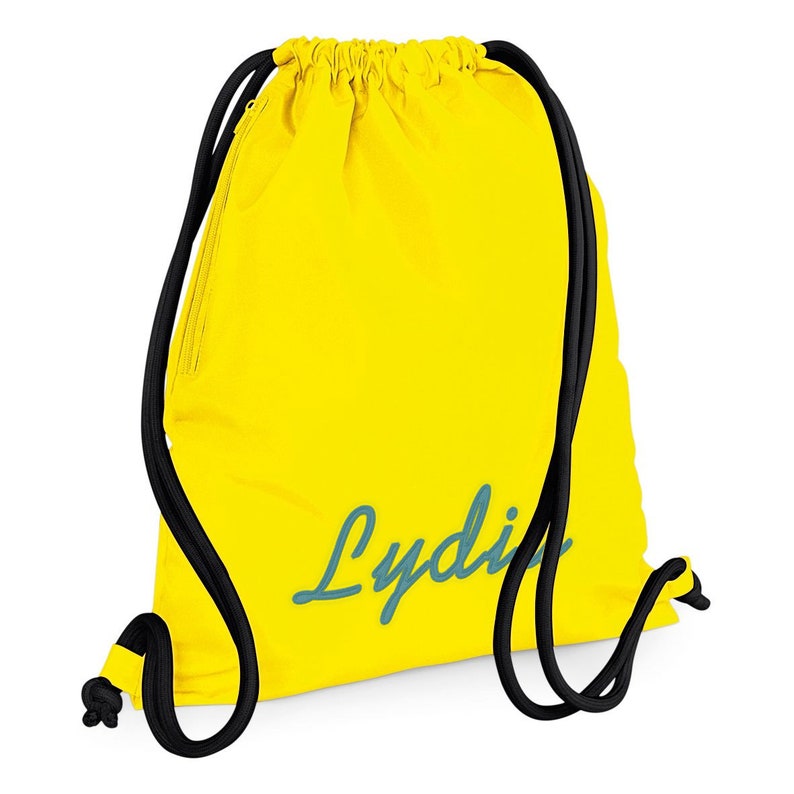 Puede incluir: Bolsa de cord&oacute;n amarilla con cordones de ajuste negros y una inscripci&oacute;n azul turquesa que dice "Lydi".