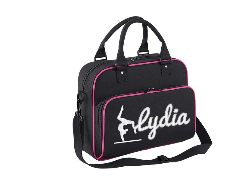 May include: Black gym bag with pink trim and a white embroidered gymnast silhouette and the name "Lydia".