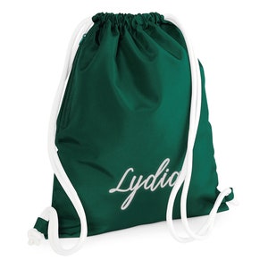 Puede incluir: Una bolsa de cord&oacute;n verde con cordones blancos y el nombre "Lydia" bordado en blanco en la parte delantera.