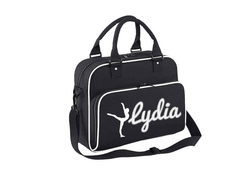 May include: Black canvas gym bag with a white trim and a white silhouette of a dancer with the name "Lydia" embroidered in white.
