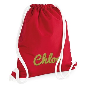 Puede incluir: Mochila de cord&oacute;n roja con cordones blancos y un nombre bordado en oro "Chloe" en la parte delantera.