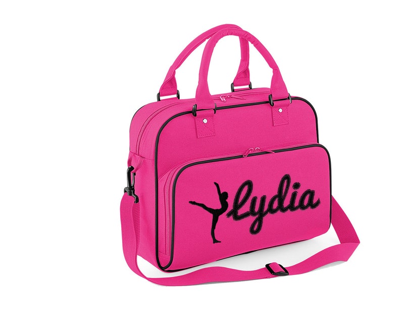 May include: Pink canvas dance bag with a black silhouette of a dancer and the name "Lydia" embroidered on the front.