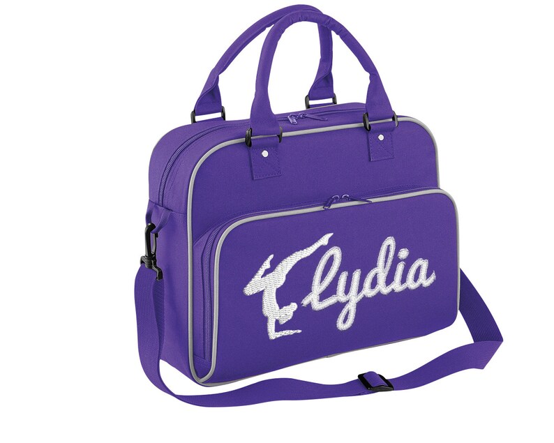 May include: Purple gym bag with a white embroidered gymnast silhouette and the name "Lydia".