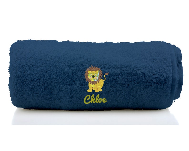 K&ouml;nnte beinhalten: Ein dunkelblaues Handtuch mit einem gelben L&ouml;wen, der eine Taucherbrille tr&auml;gt, und dem Namen "Chloe" bestickt.