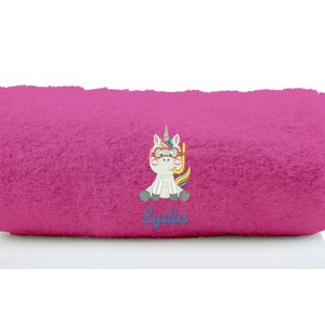 K&ouml;nnte beinhalten: Rosa Strandtuch mit einer gestickten Einhorn, die einen Schnorchel und eine Taucherbrille tr&auml;gt. Das Handtuch tr&auml;gt den Namen "Lydia" unter dem Einhorn.