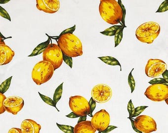 May include: White fabric with a repeating pattern of yellow lemons and green leaves. The lemons are in various stages of ripeness, some are whole and some are sliced.