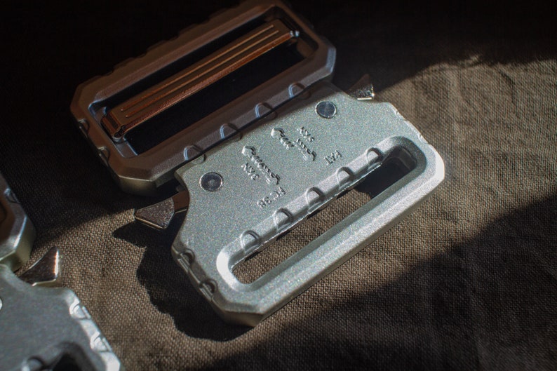 May include: A silver metal belt buckle with a sliding buckle mechanism. The buckle has the text "Made in USA" and "8621" engraved on it.