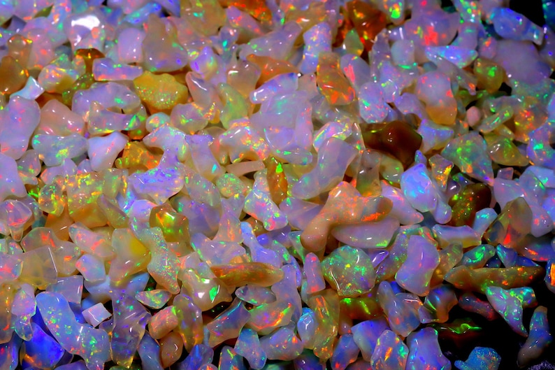 May include: A close-up view of a collection of iridescent opal gemstones. The opals are various shapes and sizes, with a rainbow of colors shimmering on their surfaces.