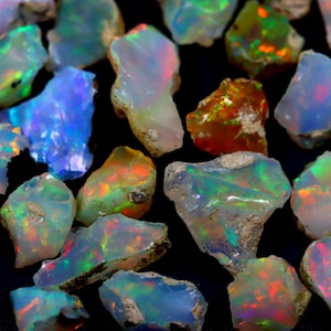 May include: A collection of rough opal gemstones in various shades of blue, green, red, and orange. The opals are iridescent and have a natural, unpolished finish.