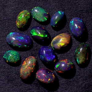 Pode incluir: Uma cole&ccedil;&atilde;o de 13 opalas pretas de forma oval com cores iridescentes verdes, azuis e vermelhas.