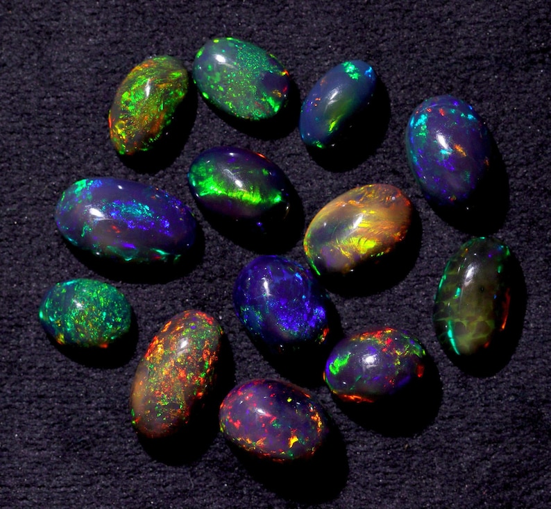 Pode incluir: Uma cole&ccedil;&atilde;o de 13 opalas pretas de forma oval com cores iridescentes verdes, azuis e vermelhas.