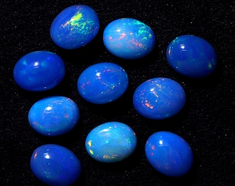 May include: Ten oval-shaped blue opals with iridescent flashes of color. The opals are arranged in a circular pattern on a black background.
