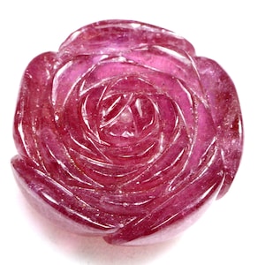 May include: A carved ruby rose, a deep red gemstone, with intricate details and a polished finish.