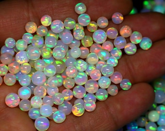 May include: A collection of iridescent opal beads in various shades of white, pink, and green. The beads are round and have a smooth, polished finish.