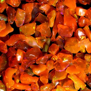 Könnte beinhalten: Nahaufnahme eines Haufens orangefarbener und roter Edelsteine. Die Steine sind glatt und poliert und haben verschiedene Formen und Größen.