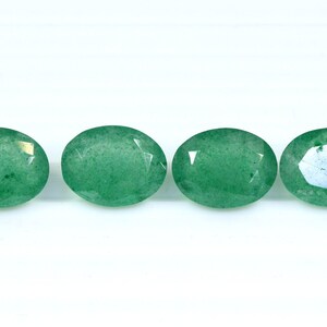 May include: Four oval-shaped green gemstones with a slightly translucent appearance.