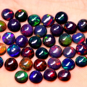 May include: A collection of 30 round, black opal cabochons, each displaying a variety of iridescent colors, including green, blue, red, and purple.
