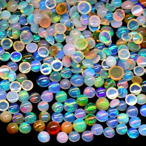 May include: A collection of iridescent opal cabochons in various sizes and shades of white, blue, green, and orange. The cabochons are round and have a smooth, polished surface.
