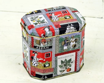 May include: A vintage, octagonal, metal tea tin with a colorful, illustrated design featuring people, plants, and ships. The tin has a gold trim and the words "Assam" and "Pekomotier" are visible on the front.