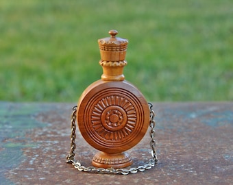 Könnte beinhalten: Eine Holzflasche mit einem geschnitzten Design und einer Metallkette. Die Flasche hat einen runden Körper und einen dekorativen Deckel.