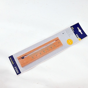 Op de afbeelding: Een houten thermometer met een heldere glazen buis en een Celsius-temperatuurschaal. De thermometer is gemonteerd op een lichtbruine houten basis en verpakt op een wit en blauw kartonnen achterkant. De merknaam "TFA" is zichtbaar.
