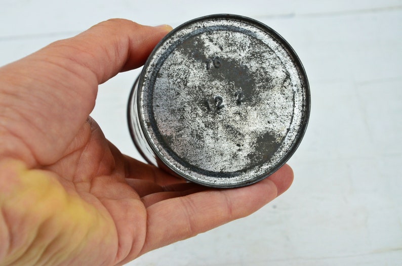 May include: Close-up of the bottom of a silver metal tin with the numbers 1/6 and 1/2 printed on the bottom.