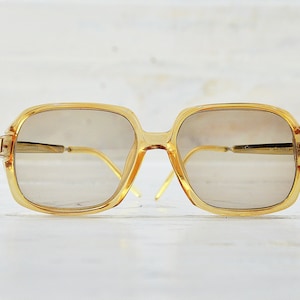 May include: A pair of vintage gold-toned square-shaped eyeglasses with brown lenses.