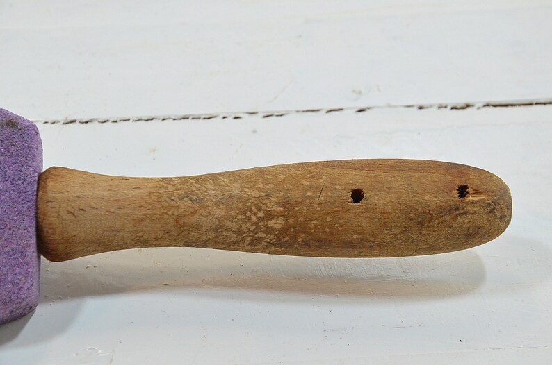 Puede incluir: Un mango de madera con dos agujeros perforados. El mango est&aacute; unido a una esponja morada.