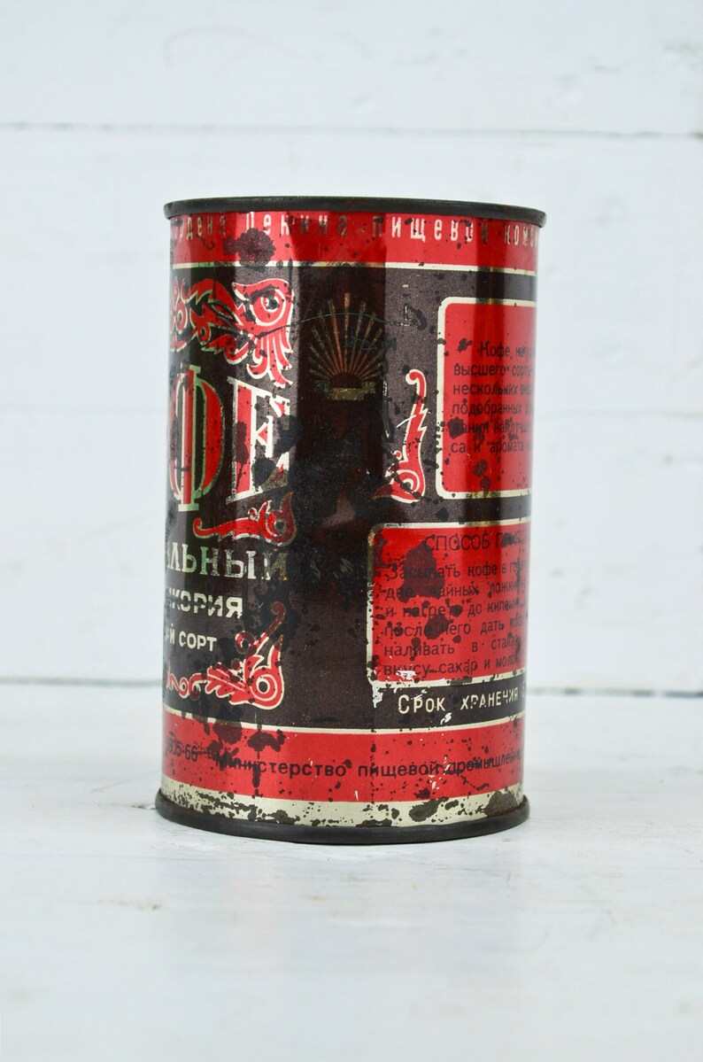May include: A vintage metal can of coffee with red and black lettering. The can is labeled "Кофе" and "Высшего сорта".