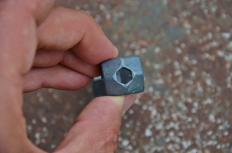 K&ouml;nnte beinhalten: Nahaufnahme einer sechseckigen silbernen Metallmutter mit einem quadratischen Loch in der Mitte.