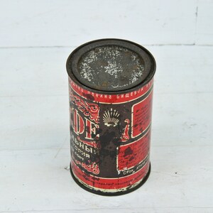 May include: A vintage metal can with a red and black label. The label features the text "Кофе" in Cyrillic script, which translates to "Coffee". The can is slightly rusted and shows signs of wear.