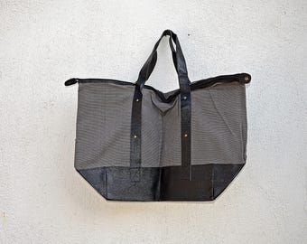 May include: A gray canvas tote bag with black leather trim and handles. The bag has a zipper closure and a large main compartment.