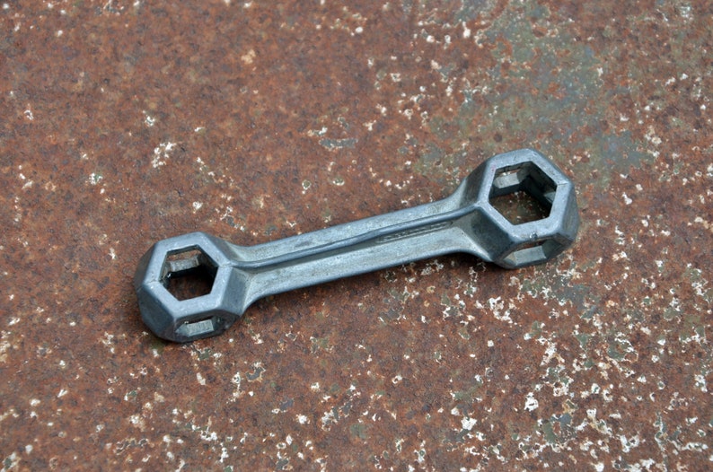 K&ouml;nnte beinhalten: Ein silberner Schraubenschl&uuml;ssel mit zwei sechseckigen &Ouml;ffnungen. Der Schraubenschl&uuml;ssel liegt auf einer rostigen Metalloberfl&auml;che.