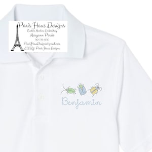 May include: White polo shirt with embroidered bugs and the name "Benjamin" on the front. The shirt is a light blue color and has a small collar. The bugs are green, blue, and yellow.