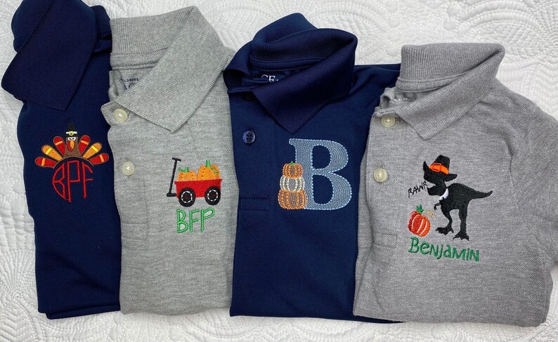 Puede incluir: Cuatro polos bordados con temas de Acci&oacute;n de Gracias. La primera camisa es azul marino con un pavo rojo y el monograma "BFP". La segunda camisa es gris con un carro rojo con calabazas y el texto "BFP". La tercera camisa es azul marino con una letra "B" azul y una pila de calabazas. La cuarta camisa es gris con un dinosaurio negro con un sombrero de peregrino y el texto "RAWR Benjamin".