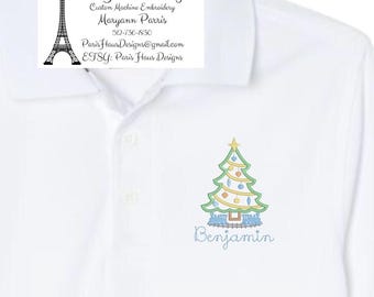 May include: White polo shirt with a green and yellow embroidered Christmas tree and the name "Benjamin" underneath. The shirt also has a small embroidered logo with the text "Paris Haus Designs" and a phone number.