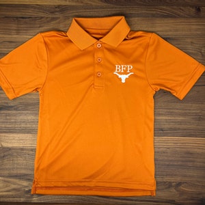 May include: Orange polo shirt with a white embroidered logo that says "BFP" and a white Longhorn steer head.