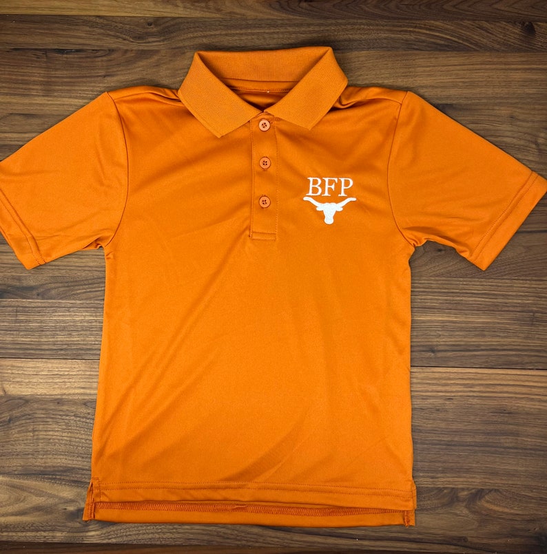 May include: Orange polo shirt with a white embroidered logo that says "BFP" and a white Longhorn steer head.