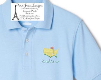 Può includere: Polo blu chiaro con un design da campo da golf ricamato sul davanti. Il design include un contorno mappa giallo, una bandiera rossa e bianca e il nome "andrew" in corsivo verde. La camicia ha un colletto e una chiusura con bottoni.