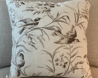 May include: A square throw pillow featuring a cream-colored fabric base with a monochromatic taupe-brown botanical print. The design displays multiple birds perched on or flying among detailed illustrations of tall grasses and small flowers.