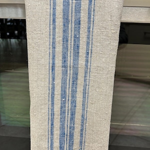 May include: A linen kitchen towel with blue stripes. The towel has a frayed edge and is hanging on a silver oven door.