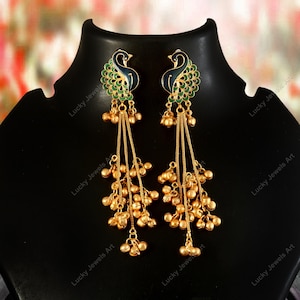 May include: A pair of gold-colored earrings with a peacock design. The earrings feature a peacock head with blue and green enamel detailing. Long chains with small gold beads hang from the peacock design.