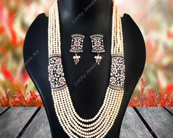 May include: A multi-strand pearl necklace with a large, ornate pendant and matching earrings. The pendant and earrings are silver-toned and feature a floral design with clear stones.