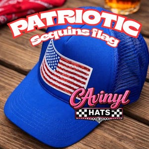 May include: A blue trucker hat with a mesh back and a curved brim. The front of the hat features a sequined American flag design. The text "PATRIOTIC sequins flag" is arched above the flag, and "CAvinyl HATS" is below.