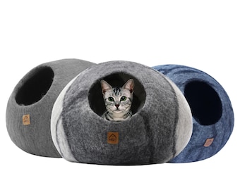 May include: Three gray and blue felt cat beds in the shape of a dome. One bed has a cat inside looking at the camera.
